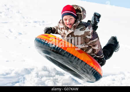 Junge, in der Luft über einen Schlauch in den Schnee Stockfoto