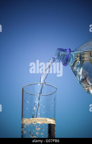 Das Wasser fließt aus der Plastikflasche in ein Glas
