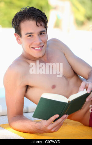 Mann legte auf Strandtuch Buch Stockfoto
