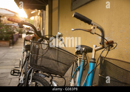 Italienische Fahrräder mit Körben auf leere sonnige Straße geparkt Stockfoto