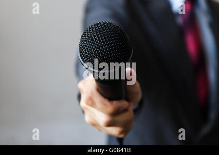 Mann im Anzug hält ein Mikrofon führen ein Geschäft Interview, Journalistin, öffentlich zu sprechen, drücken Sie Stockfoto