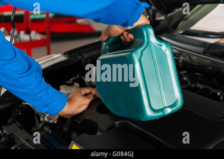 Service Mechaniker gießt neues Öl Schmierstoff in den Automotor. Stockfoto