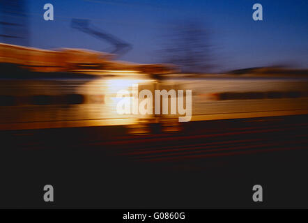 Pan verwischen Bewegung Blick auf die untergehende Sonne reflektiert Weg von SEPTEN Pendler Zug Auto Stockfoto
