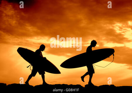 Urlaub-Silhouette der beiden Surfer tragen ihre Boards Heimat bei Sonnenuntergang Stockfoto