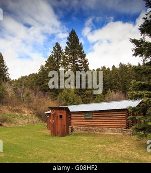 Blockhaus und rustikale Dependance in einem Wald in Montana. Stockfoto