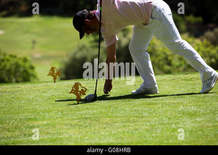 Golfspieler seinen Ball am Abschlag zu platzieren Stockfoto