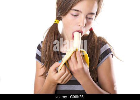 Teenager-Mädchen mit Banane in hier Mund, isoliert auf weiss Stockfoto