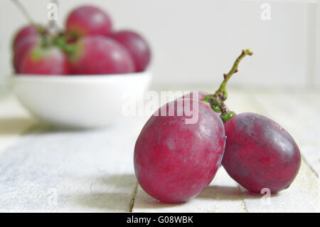 Einige Trauben auf einem weißen Holztisch einer rustikalen Küche. Leere Kopie Platz für Text Editor. Stockfoto