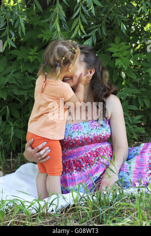 Kleines Mädchen zärtlich küsst und umarmt seine Mutter. Stockfoto