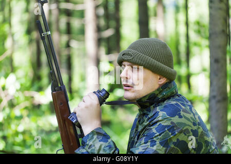 Mann mit optischen Gewehr und ein Fernglas im Holz Stockfoto