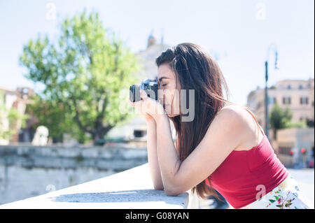 Junge Frau nehmen Foto von der Brücke in einer Stadt mit Vintage-Kamera im freien Stockfoto