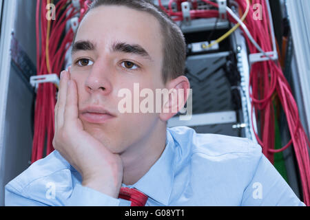 Nachdenkliche Jüngling sitzt vor einem server Stockfoto