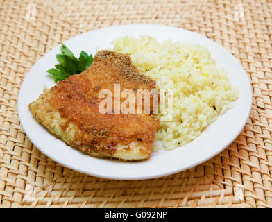 Gebratene panierte Tilapia, serviert mit Reis und Kräutern Stockfoto