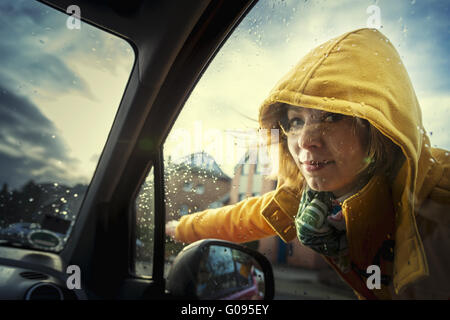 junge Frau, die auf ein Auto und zeigt den direkten Stockfoto