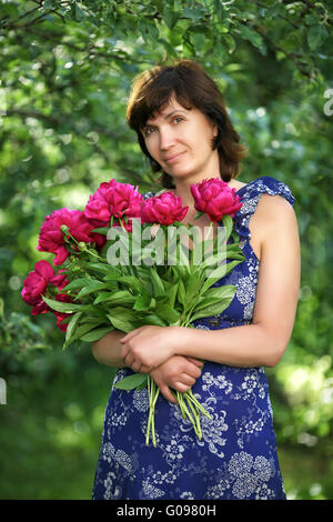 Die durchschnittliche Frau mit Blumen in einem Garten Stockfoto