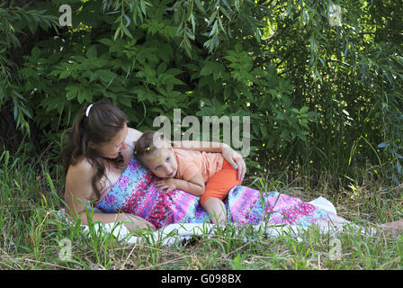 Schöne schwangere Frau beschäftigt sich zärtlich mit einer kleinen Tochter. Stockfoto