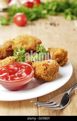 Gebratene Hähnchen-Nuggets auf dem Teller auf dem Holztisch Stockfoto