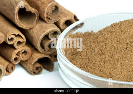 Gepulvertem Zimt in Schüssel und Zimt-sticks Stockfoto