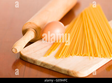 Schneidbrett aus Holz mit Ei und Teigwaren aufgestapelt, rolling Pin auf Schreibtisch neben dem Stockfoto