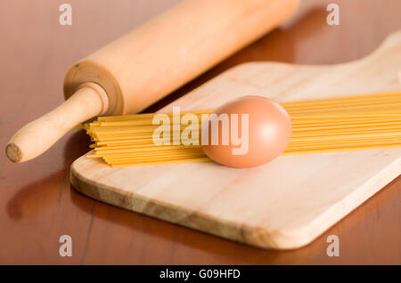 Schneidbrett aus Holz mit Ei und Teigwaren aufgestapelt, rolling Pin auf Schreibtisch neben dem Stockfoto