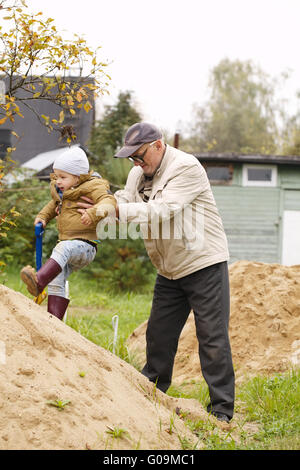 Opa hilft Enkel auf einem Sandhügel Stockfoto