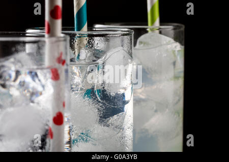 Set von drei Collins Glas mit Cocktails und bunte Strohhalme. Geschmolzene Eiswürfel dekoriert. Stockfoto