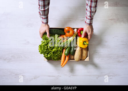 Bauer hält eine Holzkiste gefüllt mit frisch geernteten Gemüse aus seinem Garten Stockfoto