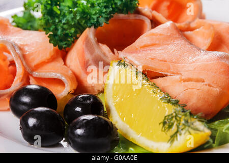 Scheiben von roter Fisch mit Zitrone und Oliven auf Platte Stockfoto