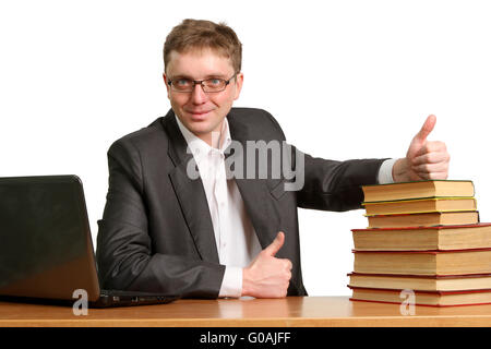 junger Kerl arbeitet an einem Laptop zeigt eine Daumen-hoch-Geste zu sagen, dass Bücher aus Papier besser sind Stockfoto