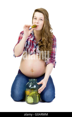 Schwangere junge Frau auf einem weißen Hintergrund frisst saure Gurken Stockfoto