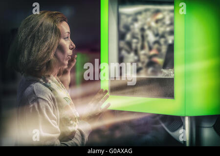eine junge Frau steht hinter einer Glasscheibe und sehen Stockfoto