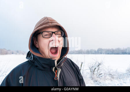 Oberkörper des gähnenden Menschen vor Schneedecke Stockfoto