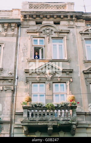 Hübscher schwarzen Haaren junger Mann im Anzug hält Brautstrauß und Blick durch Fenster Stockfoto