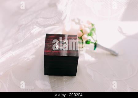 Goldenen Ehering in Box und Rosenblüten auf der Seite. Stockfoto