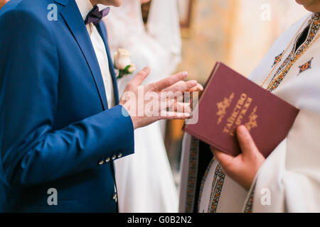 Der Priester Kleider Ring am Finger, während kirchliche Hochzeit Bräutigam Stockfoto