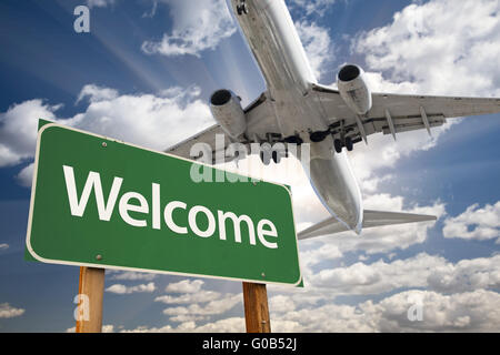 Grüne Verkehrszeichen und Flugzeug oben begrüßen Stockfoto