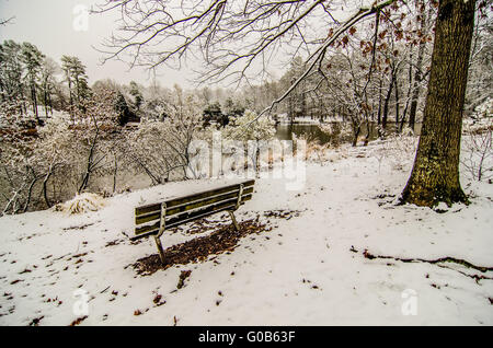 Parkbank im Schnee bedeckt Park mit Blick auf See Stockfoto