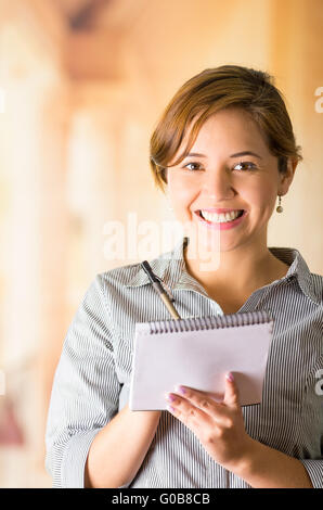 Junge Brünette Kellnerin mit freundlichen Lächeln die Bestellung schriftlich auf Notepad, Restaurant Hintergrund Stockfoto