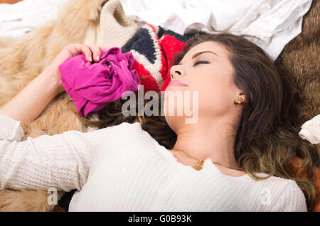 Brünette Frau liegend auf Haufen Kleider lächelnd posiert natürlich Einkaufen Modekonzept Stockfoto