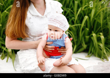 Niedliche glückliches Kind in lustigen Hut auf Mutter Knien sitzen. Familienspaß. Selektiven Fokus. Stockfoto