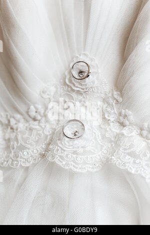 Trauringe auf ein Brautkleid liegen. Nahaufnahme, Makro, selektiven Fokus. Stockfoto