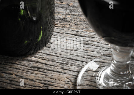 Flasche Wein und ein Glas Rotwein am rustikalen Tisch Stockfoto