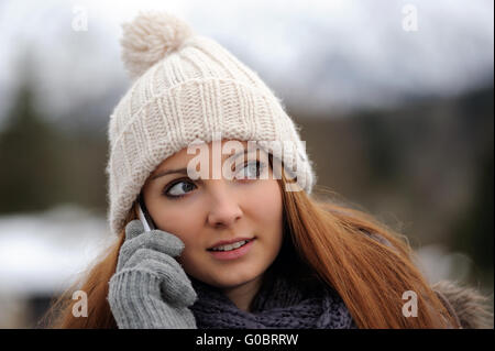 Junge Frau mit mobilen tragen Winter Kleidung Stockfoto