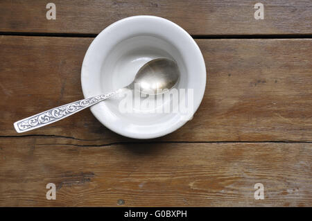 leere Suppenschüssel mit Vintage Silber Löffel auf die Holzküche Tabellenhintergrund Stockfoto