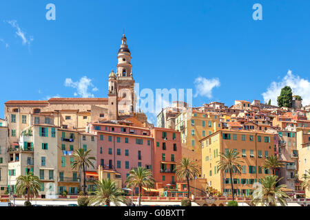 Glockenturm zwischen bunten Häusern unter blauem Himmel in der Altstadt von Menton, Frankreich. Stockfoto