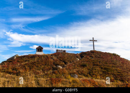 Schöne Aussicht auf winzigen Schrein und Kreuz am Berg der Schweizer Alpen, mit blauem Himmel im Hintergrund Stockfoto