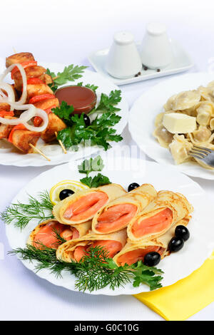 Weißen Tisch mit Essen von Fleisch, Lachs Rollen und Knödel. Stockfoto