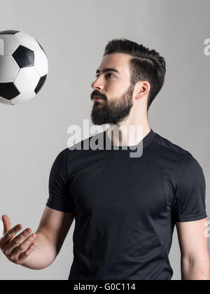 Seitenansicht des bärtigen jungen Fußball oder Fußball Spieler werfen über graue Studio-Hintergrund. Stockfoto