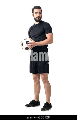 Starke zuversichtlich Fußballspieler mit Ball mit beiden Händen wegsehen. Ganzkörper-Länge-Porträt isoliert auf weißem Hintergrund Stockfoto