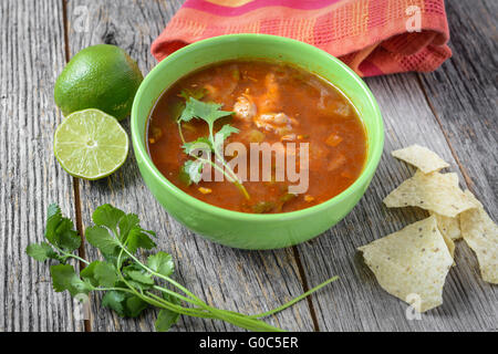Tortilla Suppe mit Pommes frites, frische Limette und Koriander auf rustikalen Holz-Hintergrund Stockfoto